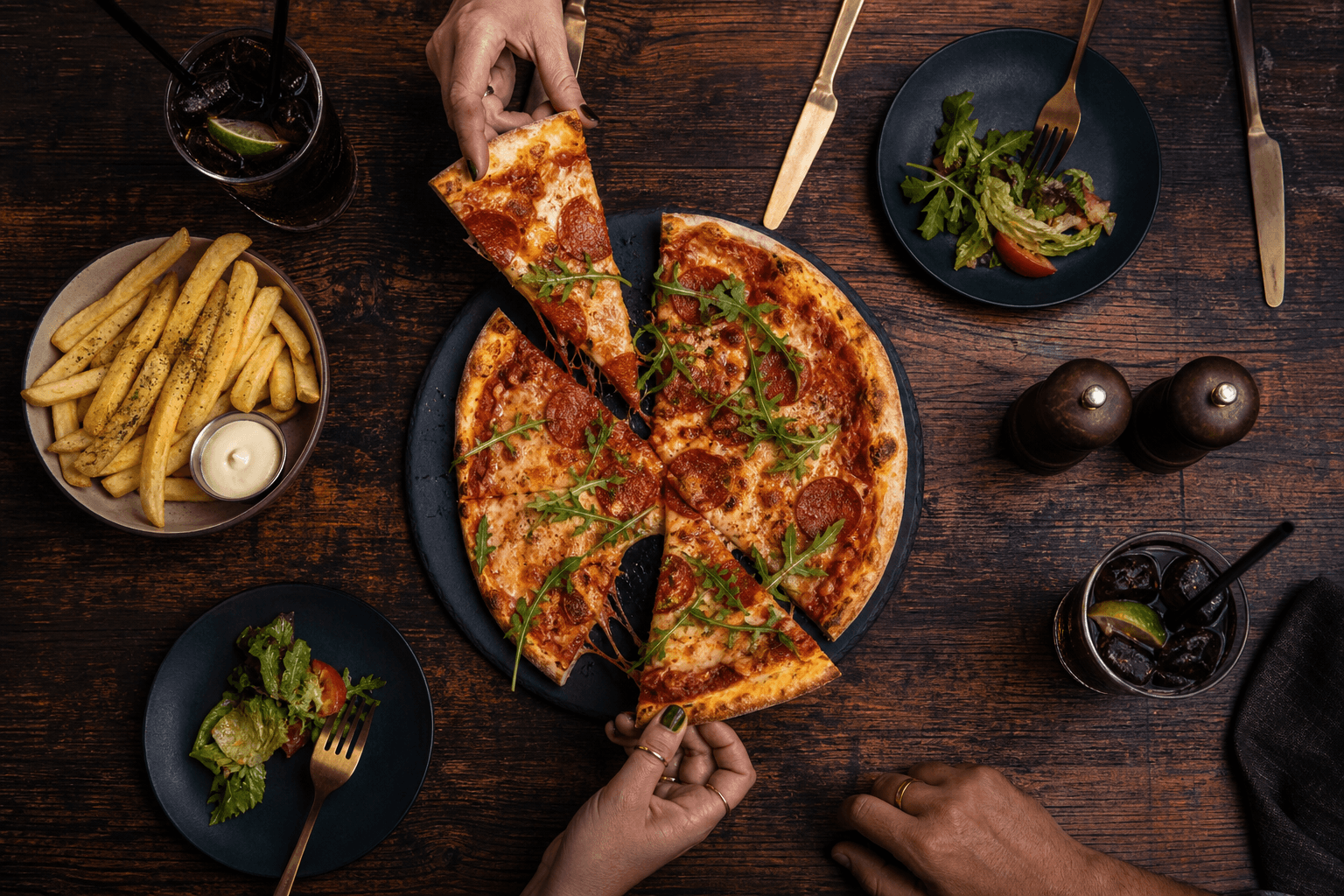 Megosztott pizza, köret és italok rusztikus asztalon